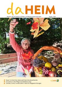 Das Titelbild der daHEIM Herbst-Ausgabe zeigt eine Bewohnerin das herbstliche Laub schwingend;